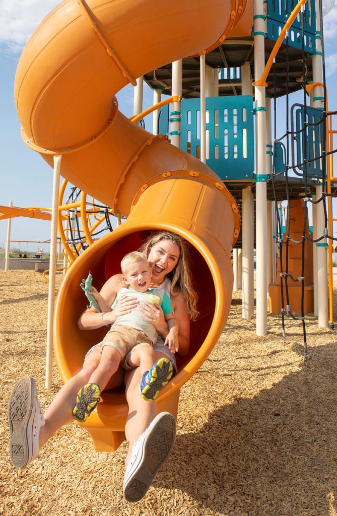 A parent and child coming out of a playground tube slide