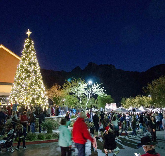 A crowd gathered around a lit Christmas tree at night