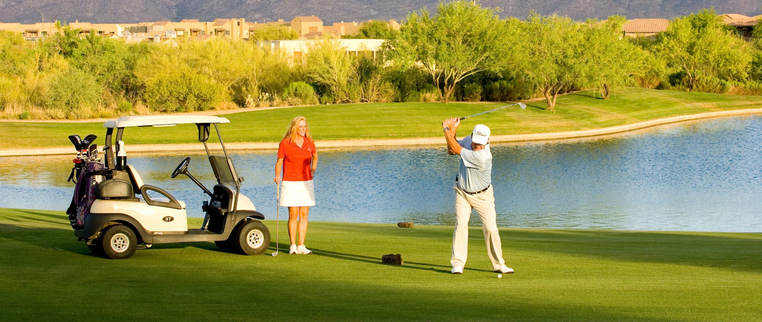Golfers on a green beside a pond