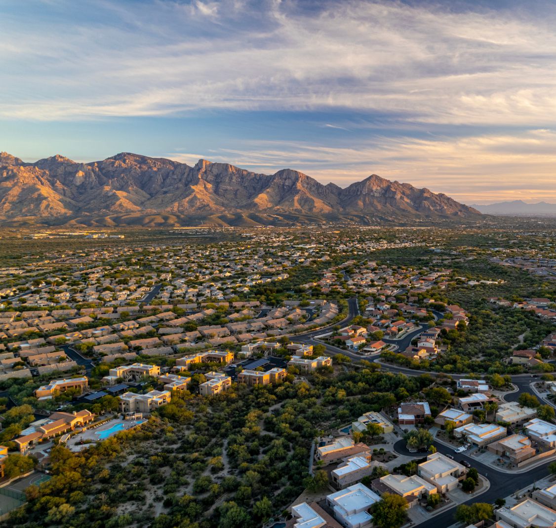 Aerial view of Oro Valley neighborhoods at sunset with the mountains behind