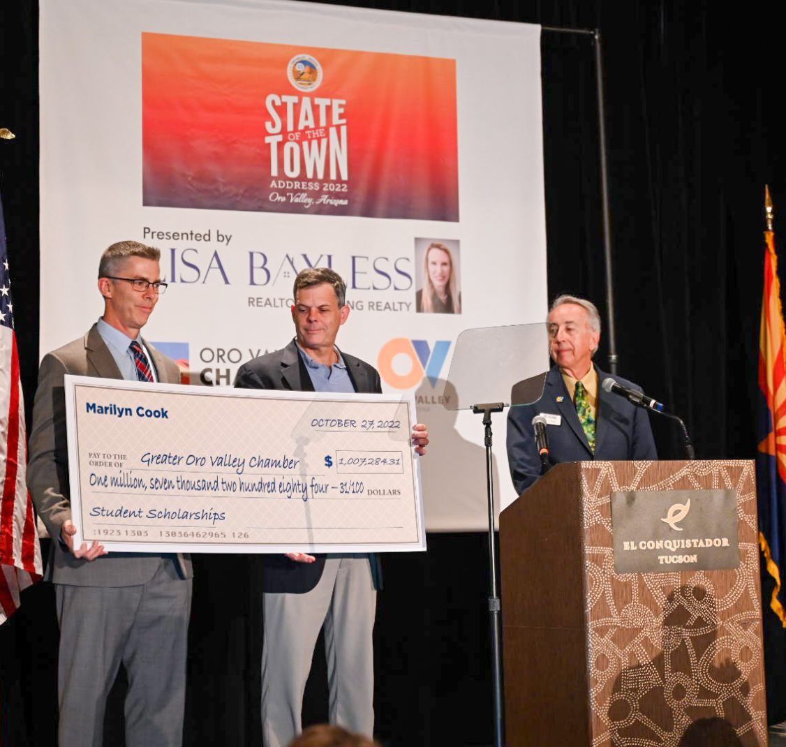 Three men on a stage with an oversized check at the State of the Town event