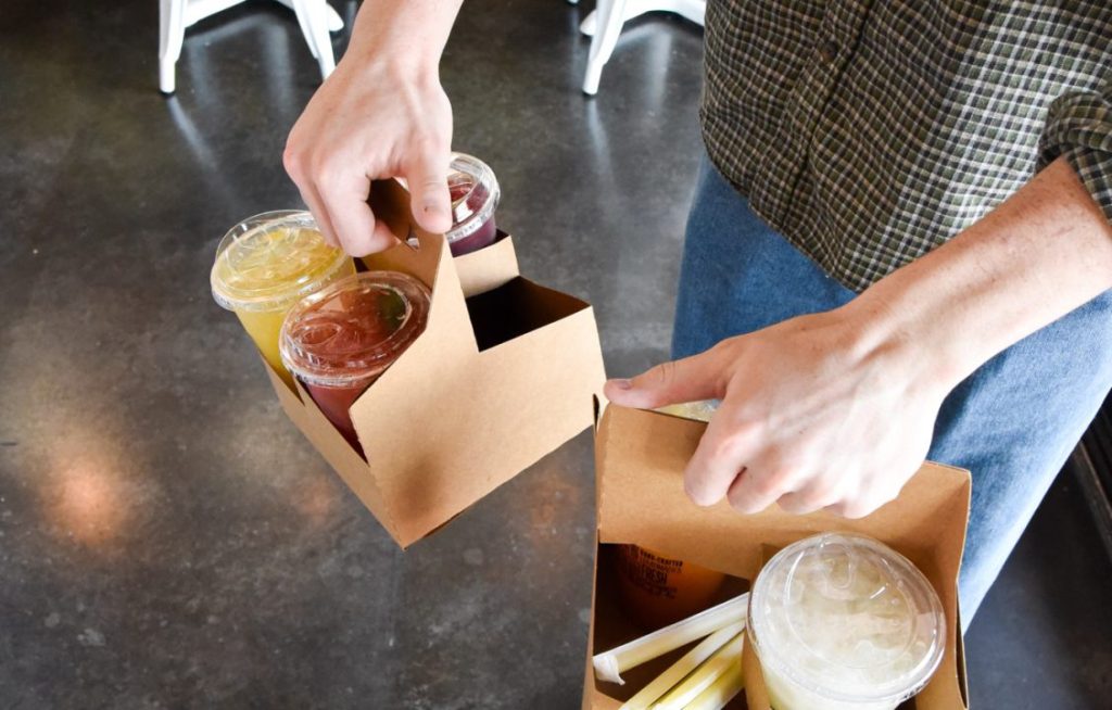Hands lifting drinks from a cardboard carrier