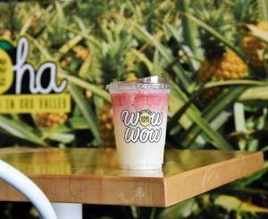 A Wow Wow lemonade on a table in front of a pineapple mural