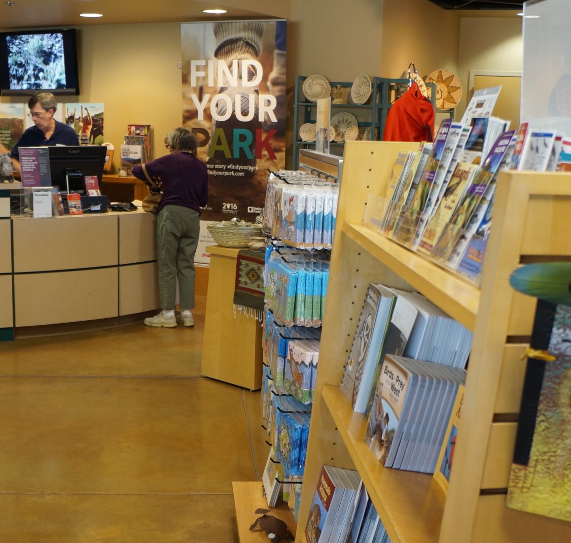 Visitors at a counter beside racks of brochures